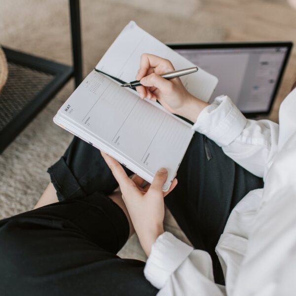 crop woman writing in notebook at home